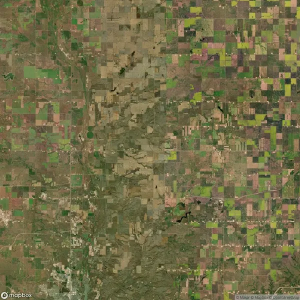 Aerial view of a patchwork landscape featuring numerous agricultural fields and mixed vegetation, intersected by roads, creating a mosaic pattern in varying shades of green and brown.