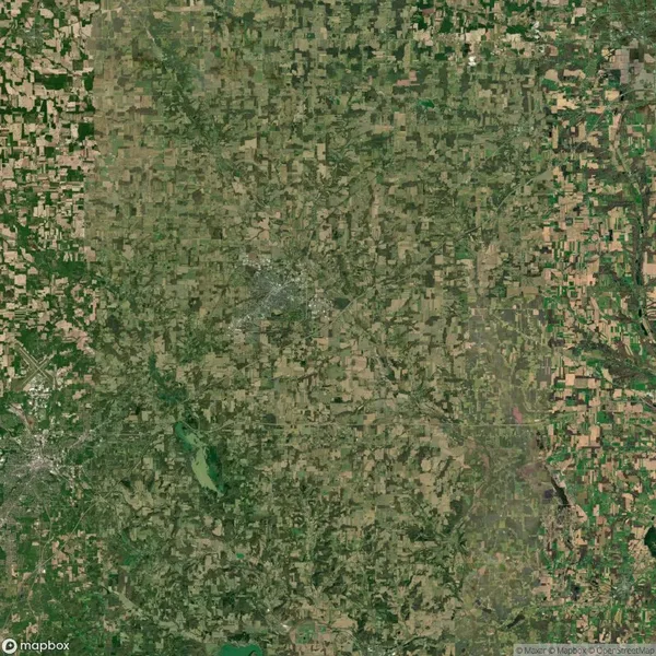 Aerial view of a rural landscape with a patchwork of green and brown fields, a few roads, and scattered small towns.