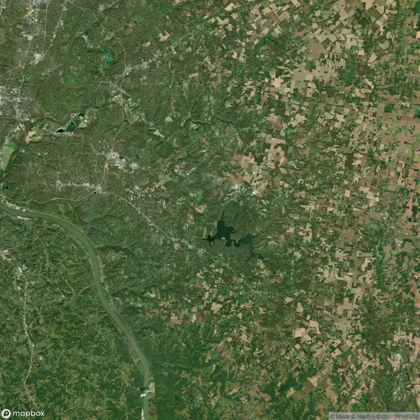 Aerial view of a wooded and agricultural landscape with a prominent river on the left and scattered fields to the right.