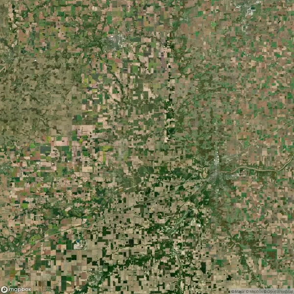 Aerial view of a rural landscape with a patchwork pattern of agricultural fields and intersecting roads. A river winds through the middle of the image.
