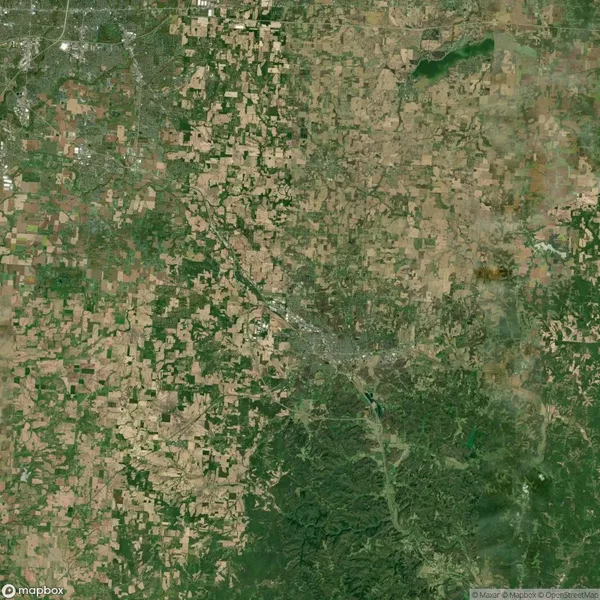 Satellite view of a landscape with a mix of green and brown patches, indicating agricultural fields and natural vegetation, intersected by a winding river.