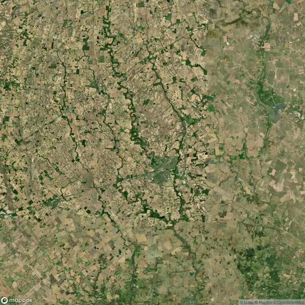 Aerial view of a landscape with a patchwork of agricultural fields and scattered green areas, intersected by meandering waterways.