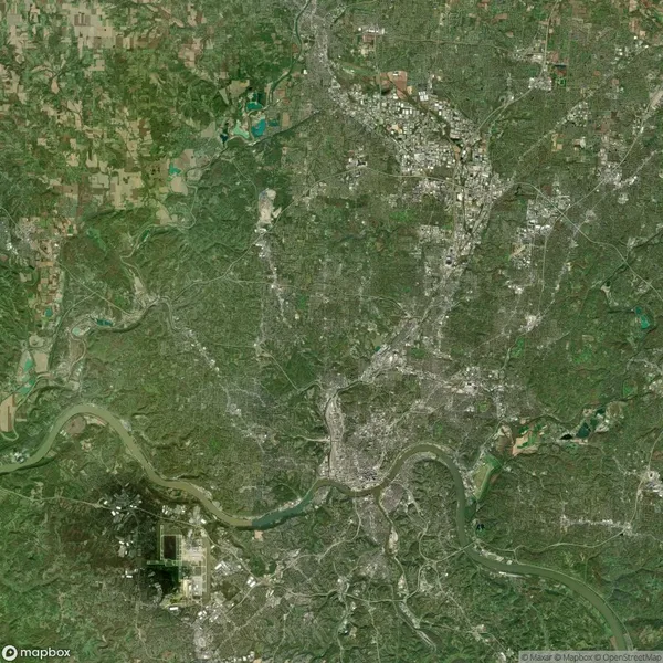 Satellite image showing a green landscape with a river flowing through a city area. Roads and buildings are visible amid a mix of urban and natural spaces.