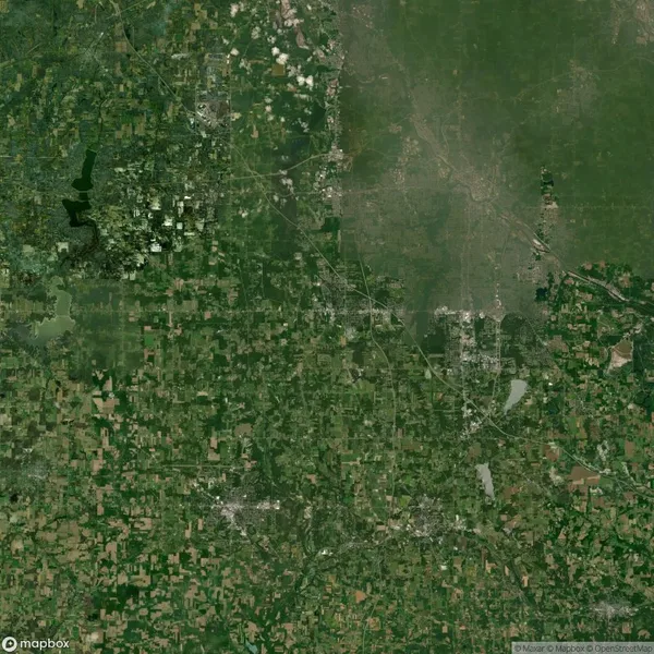 Aerial view of a green landscape with scattered urban areas, roads, and bodies of water.
