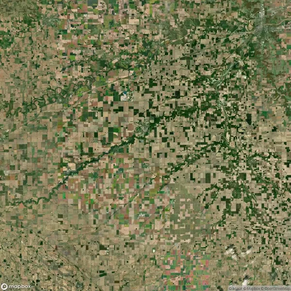 Aerial view of a rural landscape with a patchwork of agricultural fields and green areas forming irregular patterns.