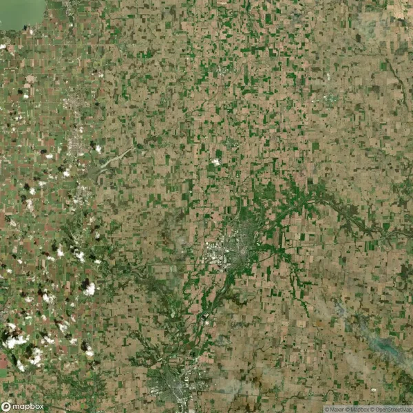 Aerial view of a patchwork of agricultural fields with varying shades of green and brown, scattered white clouds, and a river cutting through the landscape.