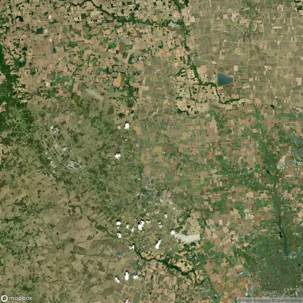 Aerial view of a patchwork landscape featuring fields, some scattered clouds, and a city in the lower right corner.