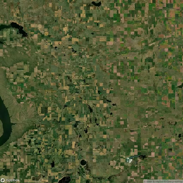Aerial view of a patchwork landscape with fields, roads, and bodies of water.