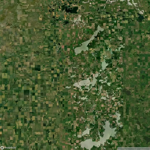 Aerial view of a patchwork agricultural landscape with scattered lakes and a mix of green fields, forests, and waterways.