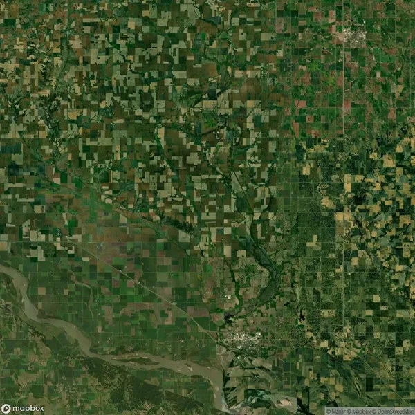 Aerial view of a patchwork of green and brown agricultural fields, with roads and a river running through the landscape.
