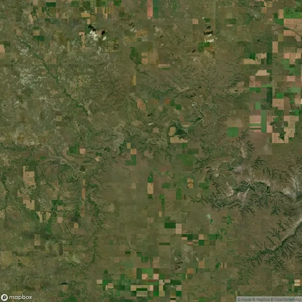 Aerial view of a patchwork of green and brown agricultural fields with winding rivers and varying terrain.