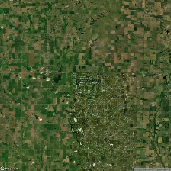 Aerial view of a landscape showing a patchwork of green agricultural fields and a rugged, less cultivated area to the south, highlighting contrast in land use.