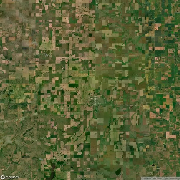 Aerial view of farmland showing a patchwork of fields with varying shades of green and brown, arranged in a grid-like pattern.