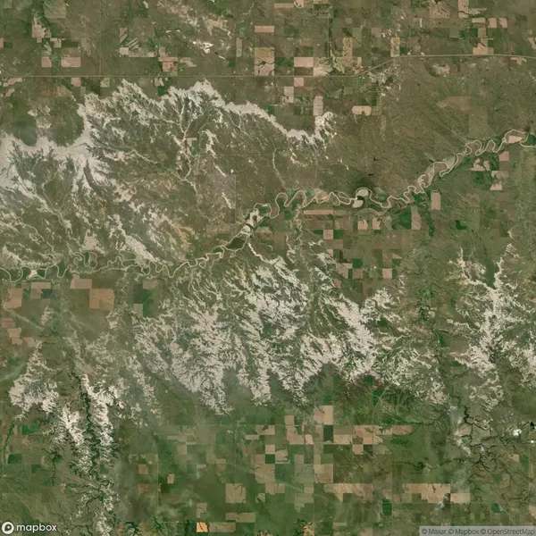Aerial view of a river winding through a landscape with a mix of farmland and natural vegetation patches, showing varied terrain and greenery.