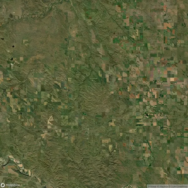 Aerial view of a rural landscape with patches of farmland, greenery, and river contours.