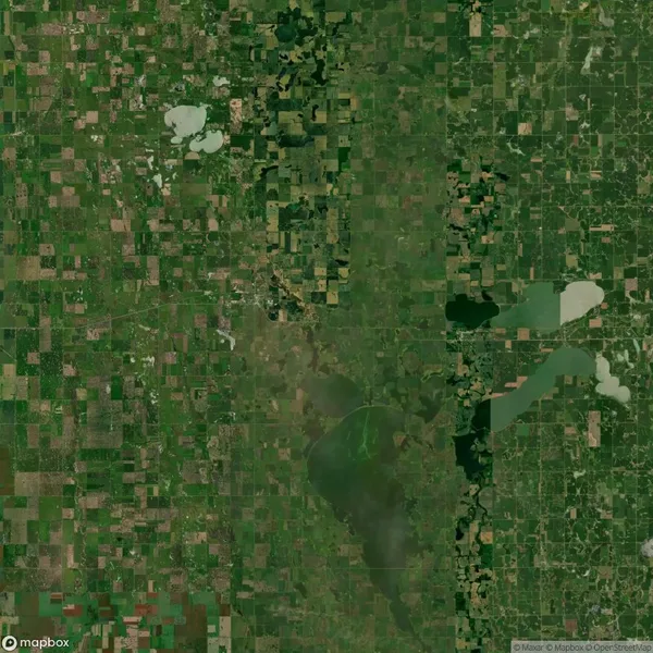 Aerial view of a patchwork landscape with green fields, lakes, and irregular grid patterns, divided by roads and vegetation, under sunny conditions.