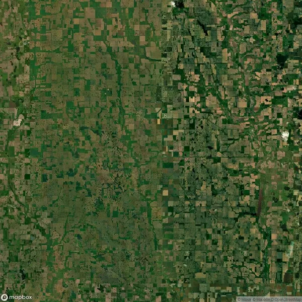 Aerial view of a sprawling landscape showing large, symmetrical patches of green and brown farmland with varying shades, indicating different types of crops and vegetation.