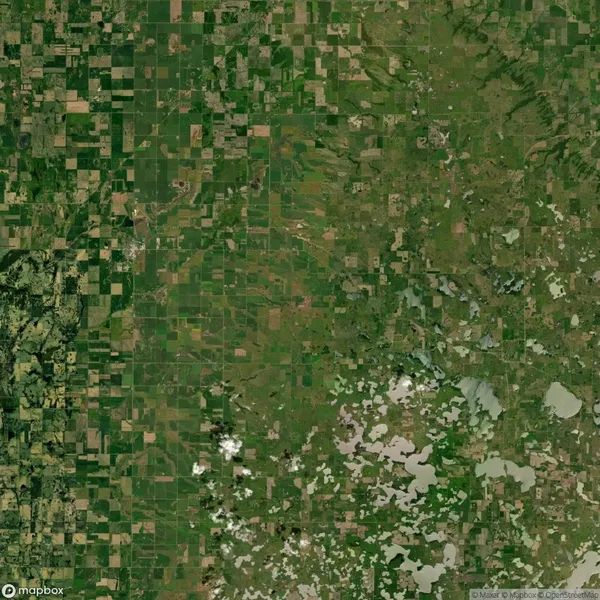 Aerial view of agricultural landscape with a grid pattern of fields and patches of greenery.