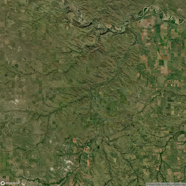 Aerial view of a landscape featuring a river coursing through a mix of farmland and rugged terrain, with varying shades of green and brown patches.