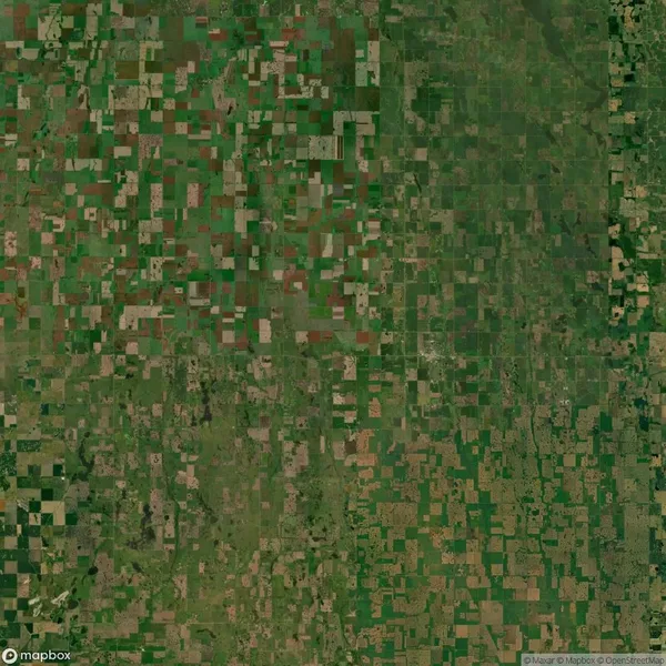 Aerial view of a patchwork agricultural landscape with various shades of green and brown fields, roads, and sparse vegetation.