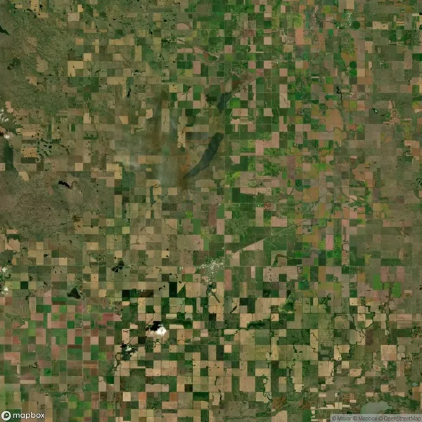 Aerial view of a patchwork landscape consisting of various rectangular agricultural fields in different shades of green and brown, indicating varied stages of cultivation.