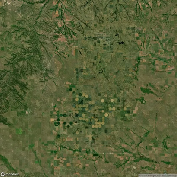Satellite view of agricultural land featuring circular and rectangular fields, surrounded by irregular terrain and patches of greenery.