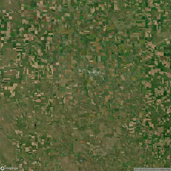 Aerial view of a patchwork landscape with a mix of green and brown agricultural fields and scattered small settlements.