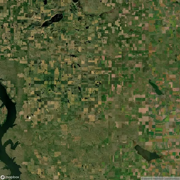 Aerial view of a patchwork landscape with green and brown agricultural fields, irregularly shaped bodies of water, and a grid-like rural road network.