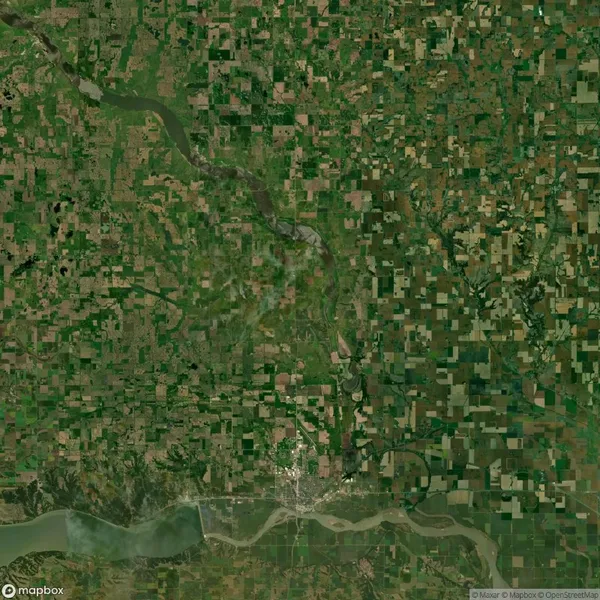 Aerial view of a rural area with a river winding through a patchwork of fields and farmland. A town and body of water are visible at the bottom of the image.