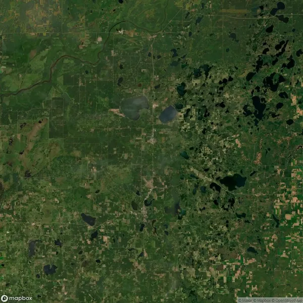 Aerial view of a green and patchy landscape with fields, forests, lakes, and rivers. Roads and small towns are scattered throughout the area.