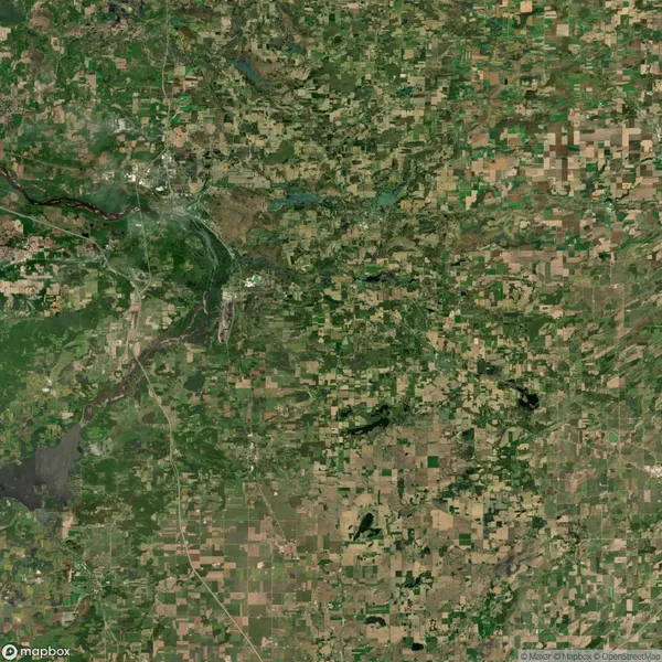Aerial view of a patchwork landscape featuring fields, roads, and scattered greenery, suggesting agricultural activity.