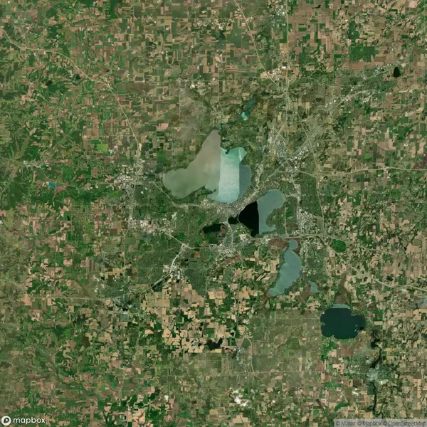 Satellite view of a landscape with multiple lakes, roads, and scattered urban areas surrounded by farmland and greenery.