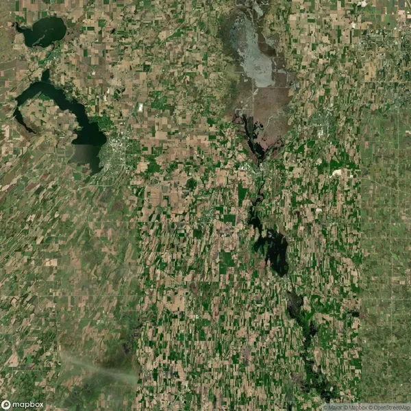 Aerial view of a rural landscape with patchwork fields and multiple bodies of water. Roads and small settlements are scattered throughout the area.
