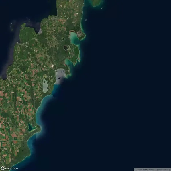 Satellite view of a coastal area featuring green land with patches of agriculture, small bodies of water, and surrounding blue ocean.