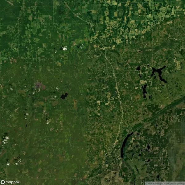 Aerial view of a green landscape with fields, forests, and scattered water bodies, intersected by roads and patches of varied vegetation.
