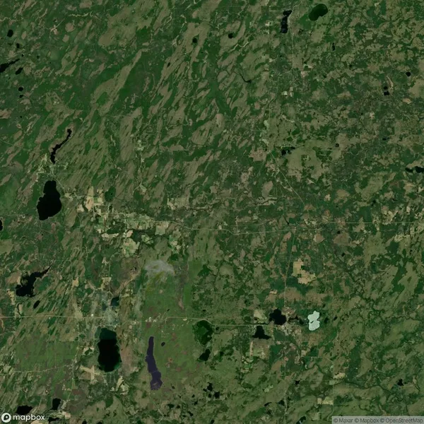 Aerial view of a landscape with scattered lakes, patches of forests, and open fields. The terrain appears varied with areas of dense vegetation and visible geographical features.