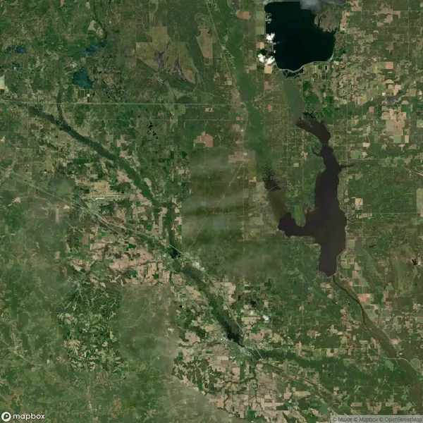 Satellite view of a green and brown landscape with rivers, lakes, and scattered agricultural fields. Urban areas are visible amid the greenery, with a large dark lake in the upper right.