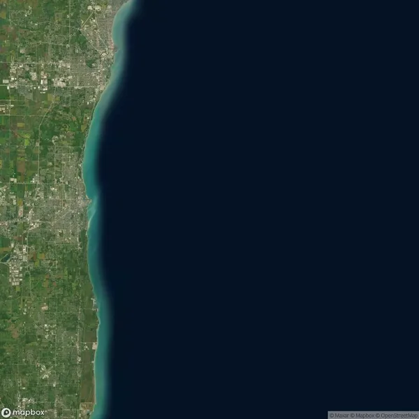 Satellite view of a coastal city with urban areas and greenery on the left, adjacent to a large body of water on the right.