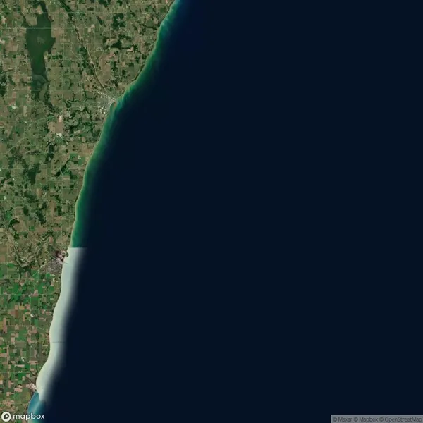 Satellite image showing the coastline of a landmass on the left with agricultural fields and a large body of water on the right.