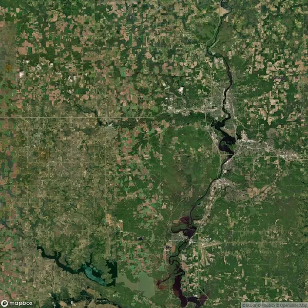 Satellite view of a landscape with a winding river, green and brown patches of land, varying vegetation, and scattered urban areas.