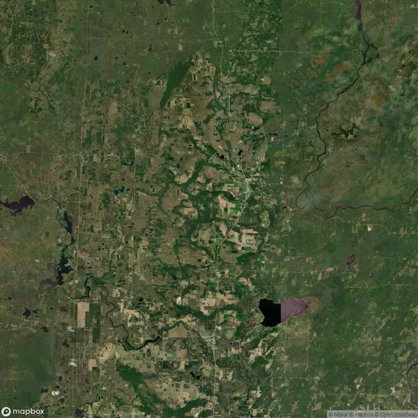 Satellite view of a landscape with patches of green fields, forests, and a winding river. A small lake is visible toward the bottom of the image.