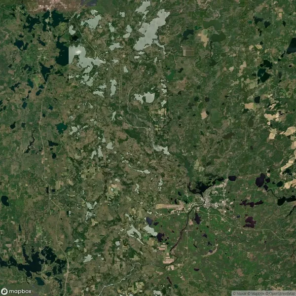 Satellite view of a green landscape with various patches of vegetation, lakes, and small settlements. Roads and rivers are visible, crossing through the terrain.