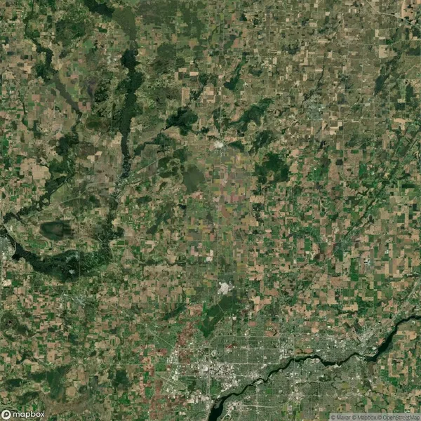 Aerial view of a patchwork landscape featuring agricultural fields, roads, and a river with a grid-like pattern of rural and urban areas.