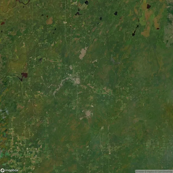 Aerial view of a large, predominantly green landscape with some scattered brown patches and irregular shapes, likely indicating vegetation and land use.