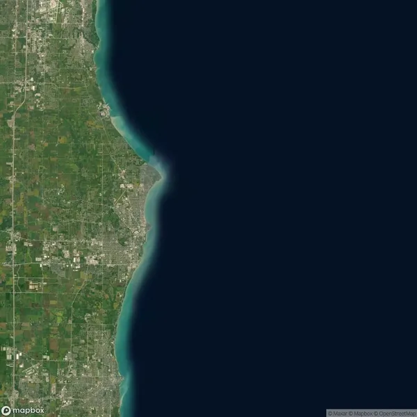 Satellite image showing the coastline of a densely populated urban area on the left, bordered by extensive water on the right. Urban and green patches are visible.