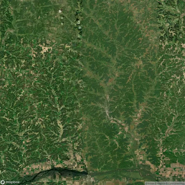 Aerial view of a landscape with dense green forest areas, scattered roads, and patches of agricultural land.
