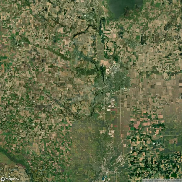 Satellite view of a region showing patchwork farmland, a winding river, and a city with grid-like streets.