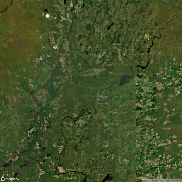Satellite view of a vast landscape with a mix of green fields, patches of water, and winding rivers. Some areas show urban development amidst natural surroundings.