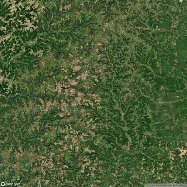Aerial view of a landscape with a sharp contrast between agricultural fields on the left and dense forested area on the right.