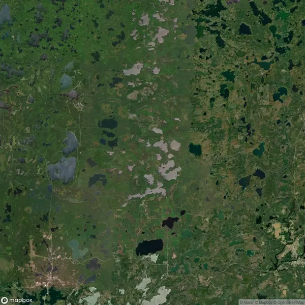 Aerial view of a green landscape with numerous lakes and patches of vegetation. Roads and small settlements are visible throughout the area.